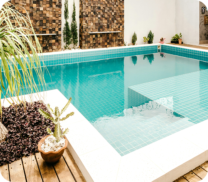 A pool with a wooden deck and plants in the middle.