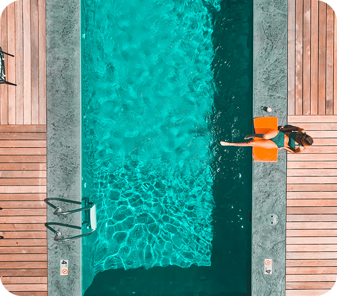 A person standing in the pool with an orange towel.